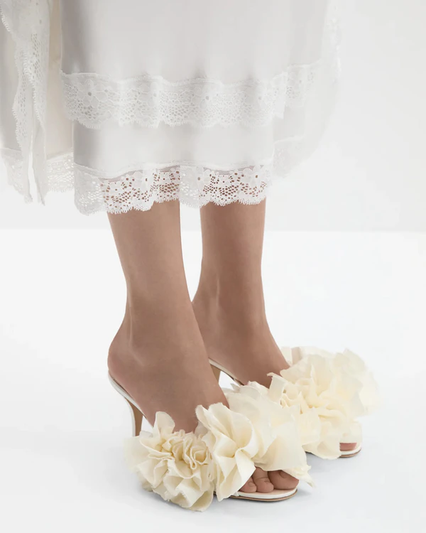 <a href="https://www.magdabutrym.com/us-en/product/pf26-mules-cream-satin-with-taffeta-flowers">MAGDA BUTRYM Satin Mules with Taffeta Flowers</a>, $1,250