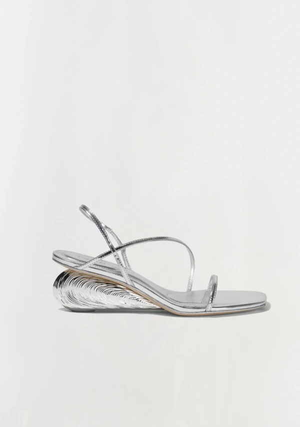 <a href="https://simkhai.com/products/bridget-oyster-shell-wedge-sandal-silver?srsltid=AU7gw4VUC__I3kGqImzXYMA_a_3_jUbftm4vNRkzOpOwsIaUmIe_zoIh">SIMKHAI Metallic Wedge Sandals, $545</a>