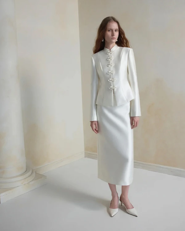 <a href="https://www.huongboutique.com/products/silhouette-jacket-cream-white?pr_prod_strat=jac&amp;pr_rec_id=c2754b894&amp;pr_rec_pid=10172386148659&amp;pr_ref_pid=10172380479795&amp;pr_seq=uniform">HUONG Jacket</a>, $240; <a href="https://www.huongboutique.com/products/blanc-taffeta-midi-skirt?pr_prod_strat=jac&amp;pr_rec_id=e8a782486&amp;pr_rec_pid=10172380479795&amp;pr_ref_pid=10172386148659&amp;pr_seq=uniform">HUONG Skirt</a> $100